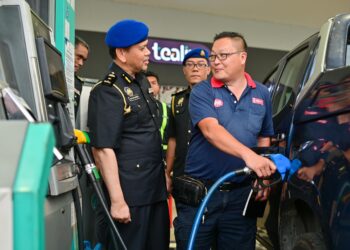 SAHARUDDIN Mohd. Kia (kiri) bertanyakan sesuatu kepada seorang pengguna yang sedang mengisi diesel di sebuah stesen minyak di Kuala Ibai, Kuala Terengganu, hari ini. - UTUSAN/PUQTRA HAIRRY ROSLI