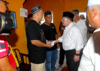 SHAMSUL ISKANDAR Mohd. Akin menyampaikan sumbangan wang tunai RM10,000 yang diterima abang Allahyarham Hadi Ashraf Mad Idris, Mohd. Zaki Mad Idris di Padang Temu, Melaka. - UTUSAN/AMRAN MULUP