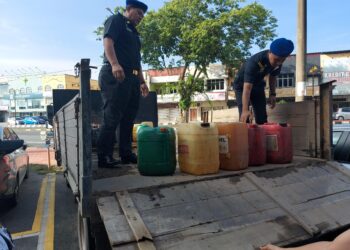 DUA anggota penguat kuasa KPDN memeriksa sebahagian diesel bersubsidi yang dirampas di Paka, Dungun, semalam.