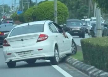 TANGKAP layar menunjukkan seorang lelaki memandu kereta sambil memegang pistol di
Jalan Sultan Mahmud, Kuala Terengganu, semalam. - MEDIA SOSIAL