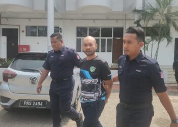 TERTUDUH (tengah) dibawa keluar dari mahkamah selepas didakwa di Mahkamah Sesyen dan Mahkamah Majistret Raub di Raub, Pahang.