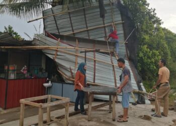 NOR FARIDA Sulaiman (kiri) mengemas kedai makan miliknya selepas dilanda ribut di Kampung Langgar, Hulu Terengganu, semalam. - UTUSAN/NOOR HAYATI MAMAT