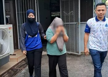 PENGASUH (tengah) yang direman tujuh hari bantu siasatan kes bayi patah tangan dan mengalami pendarahan otak dibawa keluar dari Mahkamah Kemaman, di Kemaman, hari ini. - UTUSAN/NIK NUR IZZATUL HAZWANI NIK ADNAN