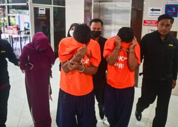 DUA pegawai penguat kuasa (baju oren) dan isteri salah seorang pegawai terbabit (dua, kiri) dibawa keluar dari Mahkamah Majistret Kuala Terengganu, hari ini. - UTUSAN/PUQTRA HAIRRY ROSLI