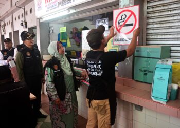 KASEMANI Embong (dua, kanan) melihat  seorang pemilik premis menampal
poster 'Dilarang Merokok' pada Operasi Cakna Undang-Undang Kesihatan Awam Siri 3/2024 di Pantai Batu Buruk, Kuala Terengganu. - UTUSAN/PUQTRA HAIRRY ROSLI