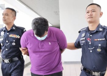 TERTUDUH diiringi anggota polis ketika dihadapkan ke Mahkamah Majistret, Ayer Keroh, Melaka. - UTUSAN/MUHAMMAD SHAHIZAM TAZALI