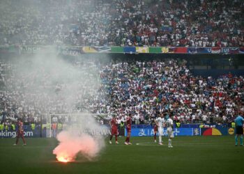 PENONTON membaling suar ke tengah padang semasa perlawanan Serbia menentang Slovenia dalam aksi Euro 2024. - AFP