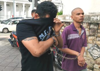 A. PRAKASH (kiri) cuba menutup wajahnya daripada dirakam lensa kamera ketika tiba di Mahkamah Sesyen dan Majistret di George Town, Pulau Pinang