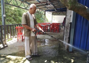 MOHD. Rais Nordin membersihkan kedai makannya yang terjejas selepas dilanda banjir kilat di pekan Nilai, Seremban lewat petang semalam.-UTUSAN/NUR SHARIEZA ISMAIL.