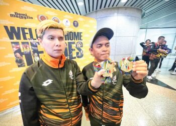 MUHAMAD Ayub Mohd (kanan) bersama Hasmiunirah Maliki menunjukkan pingat emas yang dimenangi di Kejohanan Boling Padang Para Dunia ketika ditemui di KLIA semalam.