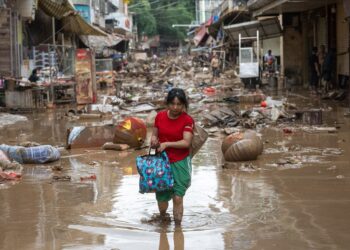 PENDUDUK terpaksa meredah jalan berlumpur ketika hujan lebat menyebabkan banjir di Meizhou, wilayah Guangdong.- ANADOLU