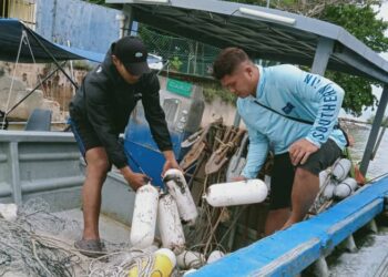 DUA nelayan di Sungai Rengit menunjukkan kesan minyak yang terkena pada peralatan mereka susulan tumpahan minyak akibat pelanggaran kapal di Singapura.