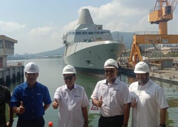 MOHAMED Khalid Nordin (tengah) bergambar berlatar belakang kapal LCS1 di Limbungan LUNAS Sdn. Bhd. di Pangkalan TLDM  Lumut hari ini. - UTUSAN