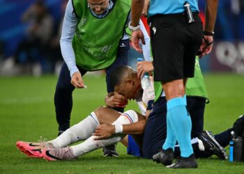 PENYERANG Perancis, Kylian Mbappe (duduk) sedang menerima rawatan daripada pasukan perubatan selepas hidungnya patah akibat perlanggaran kuat ketika menentang Austria dalam aksi Kumpulan D, Euro 2024. - AFP