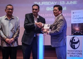 Azam Baki menerima buku The Sin Of Coruption A Religious Perspective daripada Presiden Transperancy International Malaysia, Dr Muhammad Mohan yang dilancarkan di Putrajaya semalam. – UTUSAN/FAIZ ALIF ZUBIR