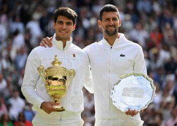 CARLOS Alcaraz (kiri) memegang trofi pemenang  dan Novak Djokovic pada perlawanan akhir  Kejohanan Wimbledon 2024 di The All England Lawn Tennis dan Kelab Croquet, London, hari ini. - AFP