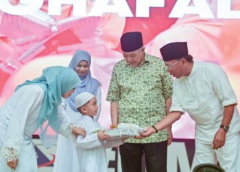 SEORANG pelajar Tabika Jabatan Kemajuan Masyarakat (Kemas) menerima modul Program Pra Tahfiz Kemas yang dilancarkan Ahmad Zahid Hamidi (dua dari kanan) peringkat Terengganu di Kuala Nerus, semalam. – MINGGUAN/PUQTRA HAIRRY ROSLI