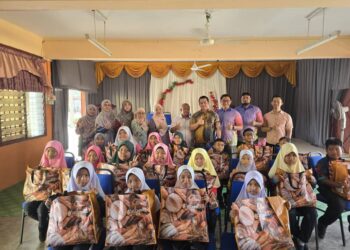 KAMARUL Azman Khamis bergambar bersama murid-murid pada program sumbangan di SK Pedu hari ini.-UTUSAN