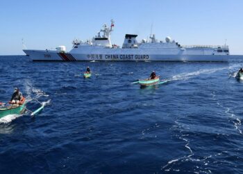 KUMPULAN nelayan Filipina melepasi kapal Pengawal Pantai China di Scarborough Shoal yang menjadi satu daripada kawasan pertikaian di Laut China Selatan. - AFP