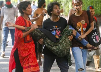 PELAJAR membawa seorang wanita yang cedera selepas penunjuk perasaan antikuota dan penyokong Liga Awami bertempur di kampus Universiti Dhaka, di Dhaka.- AFP