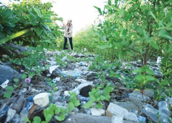 ROSNANI Nazri meninjau sampah-sarap yang memenuhi kawasan pesisir Pantai Keria, Sungai Padang, Perlis semalam. – UTUSAN/IZLIZAN OTHMAN