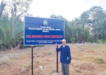 GHAZALI Baharum menunjukkan papan tanda ‘Dilarang Menceroboh’ yang dipasang di Tanah Perkuburan Islam Kampung Kemang, Batu 36, Pontian, Johor semalam.