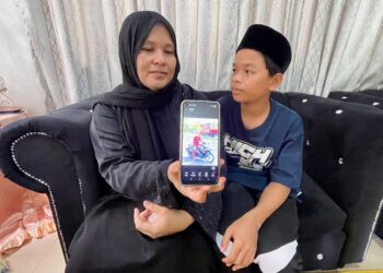 Noormiza Md. Nor di samping Muhammad Farish Muhammad Zahir menunjukkan gambar Muhammad Danish Hakim ketika ditemui di rumahnya di Alor Senjaya, Anak Bukit Alor Setar Kedah, semalam.