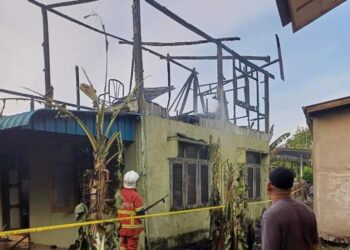 ANGGOTA bomba memeriksa keadaan rumah Che Rohana Mohamad yang terbakar di Kampung Seberang Baroh, Kuala Terengganu, semalam. - UTUSAN/TENGKU DANISH BAHRI TENGKU YUSOFF
