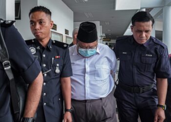 TERTUDUH diiring anggota polis selepas mengaku tidak bersalah di Mahkamah Majistret, Ayer Keroh, Melaka atas pertuduhan menampar muka pelajarnya beberapa kali dan menarik rambut mangsa. - UTUSAN/SYAFEEQ AHMAD