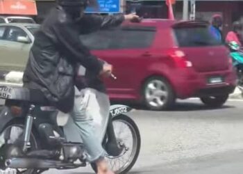 SEORANG lelaki menunggang motosikal sambil mengacukan objek menyerupai sepucuk pistol di Kuala Terengganu, hari ini. - MEDIA SOSIAL