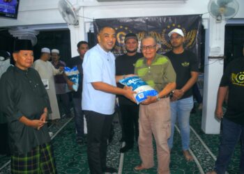 AHLI Dewan Undangan Negeri (ADUN) Duyong, Datuk Mohd. Noor Helmy Abdul Halem menyerahkan sekampit beras kepada seorang asnaf pada program agihan beras dan wang tunai di Masjid Fathur Rahman, Pengkalan Rama, Melaka. - UTUSAN/AMRAN MULUP
