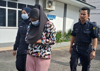 NORULHUDA Sufia Muda (tengah) yang didakwa menganiaya anak perempuannya dibawa keluar dari Mahkamah Sesyen Kemaman, hari ini. - UTUSAN/NIK NUR IZZATUL HAZWANI NIK ADNAN