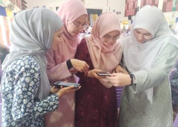 EMPAT pelajar melihat keputusan STPM melalui telefon pintar di SMK Nasiruddin, Besut, hari ini. - UTUSAN/WAN ZURATIKAH IFFAH WAN ZULKIFLI