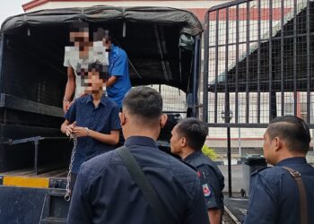 TERTUDUH (depan) dibawa ke Mahkamah Majistret Bahau, Jempol hari ini selepas dituduh menikam ibunya sendiri dalam kejadian di Felda Raja Alias 1, Jempol bulan lalu.-GAMBAR/NOR AINNA HAMZAH.