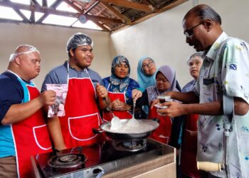 ISAIAH Jacob (kanan) melihat pelatih OKU memasak dodol ketika beliau mengadakan lawatan ke Rumah Aktiviti Pendidikan Khas Senawang di Taman Widuri Indah, Senawang, Seremban. UTUSAN/MOHD. SHAHJEHAN MAAMIN.