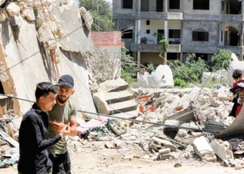REMAJA Lubnan melintas kawasan runtuhan bangunan kesan daripada serangan tentera Israel pada Isnin minggu lalu.– AFP