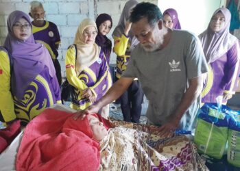 RAZALI Joli memeriksa keadaan isterinya yang terlantar di atas katil sejak tujuh tahun lalu sambil diperhatikan ahli-ahli Pertubuhan Amal Bakti Kebajikan Masyarakat Mersing di Kampung Sri Lalang, Mersing, Johor.