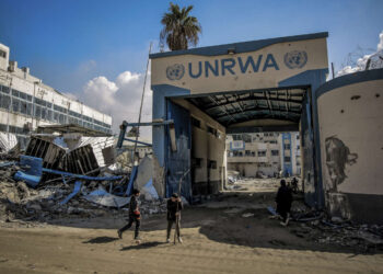 PENDUDUK Palestin berjalan di hadapan bangunan UNRWA yang musnah akibat serangan Israel di Gaza.- AGENSI