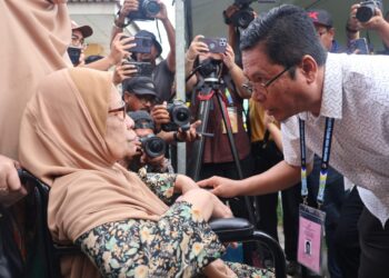 ABIDIN Ismail (kanan) bersalaman dengan ibunya, Che Refiah Zakaria ketika kedua-duanya hadir secara berasingan untuk membuang undi di SK Sungai Duri, Nibong Tebal, Pulau Pinang.