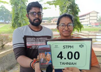 Y. SUGASHINI menunjukkan keputusan cemerlang STPM yang diperolehnya dan gambar mendiang kedua ibu bapanya sambil ditemani Sivaneshwaran ketika ditemui di Tampin hari ini.-UTUSAN/NOR AINNA HAMZAH.