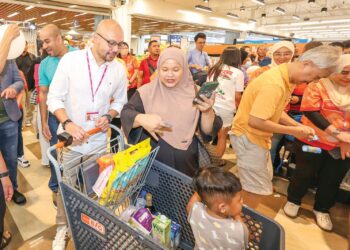 Sheikh Farouk Sheikh Mohamed (kiri) beramah mesra bersama pelanggan yang menerima baucar selepas   merasmikan Majlis Pelancaran Kempen Segalanya Besar diiringi oleh barisan penaja di AEON Big Subang Jaya, kelmarin. – UTUSAN/AMIR KHALID