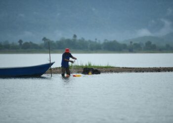 SEORANG nelayan terpaksa menolak botnya sejauh 200 meter ke tengah tasik sebelum dapat menghidupkan enjin berikutan empangan yang semakin menyusut sehingga paras 26.85 meter di Tasik Timah Tasoh, Padang Besar, Perlis semalam.-UTUSAN/IZLIZAN OTHMAN