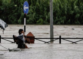 SEORANG wanita membawa barangnya sambil meredah banjir yang tercetus akibat hujan lebat di Kathmandu, Nepal.- AGENSI