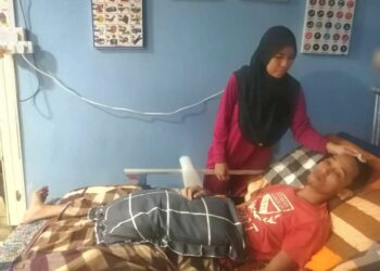 MUHAMMAD Itmam Zawahir yang terlantar sejak lebih sebulan lalu bergantung sepenuhnya kepada isteri, Siti Nur Fatin Mazlan untuk menguruskan diri di rumah mereka di Kampung Kemat, Hulu Terengganu, semalam. – UTUSAN/NOOR HAYATI MAMAT