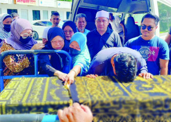 FARIDAH Mohd. Maluddin ditemani Mohd. Syahzehanuddin semasa menyambut ketibaan jenazah anak bongsunya, Mohd. Rais Sarkhanuddin di Mas Kargo, Kota Kinabalu, semalam.