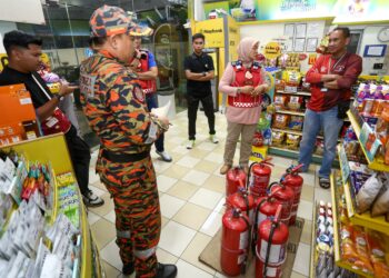 SAYANI Saidon (tengah) bersama pegawainya membuat pemeriksaan alat pemadam api di Ipoh semalam. - UTUSAN/MUHAMAD NAZREEN SYAH MUSTHAFA