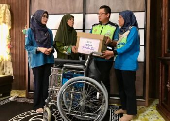 NORA Yaacob (kanan) menyampaikan sumbangan barangan keperluan dan kerusi roda kepada Rosliza Muhamad Amin di rumahnya di Kampung Manek Urai, Kuala Krai, Kelantan. - UTUSAN/ROSLIZA MOHAMED.