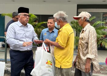 MOHD. Zolkafly Harun (kiri) menyerahkan kotak makanan hasil pertanian kepada golongan memerlukan di Ipoh hari ini. - UTUSAN/LIYANA RAMLI