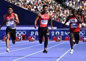 MUHAMMAD Azeem Fahmi (tengah)  bersama Ebrahima Camara (kanan) ketika bersaing dalam acara saringan pertama 100 meter (m) lelaki di Stadium Stade de France, hari ini. - AFP