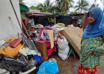 JAMILAH Man melihat timbunan barangan miliknya yang dikumpul di luar rumahnya oleh sukarelawan sebelum dibuang di Kampung Sungai Pasir, Sungai Petani.